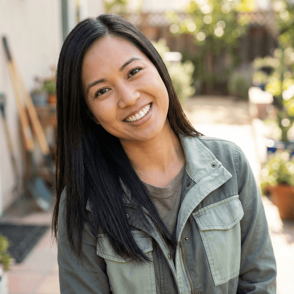 Mei Lin smiling in front of her clean brick house